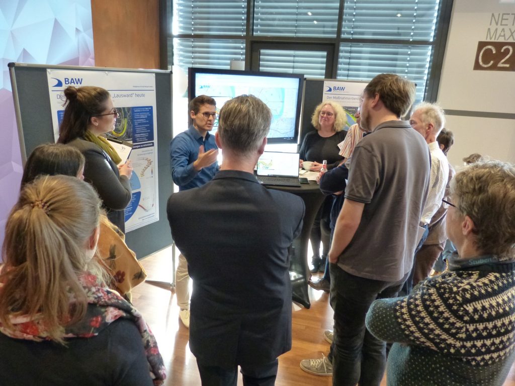 Das Bild zeigt eine Diskussionsszene am Stand der BAW im Nachgang zu den Vorträgen.